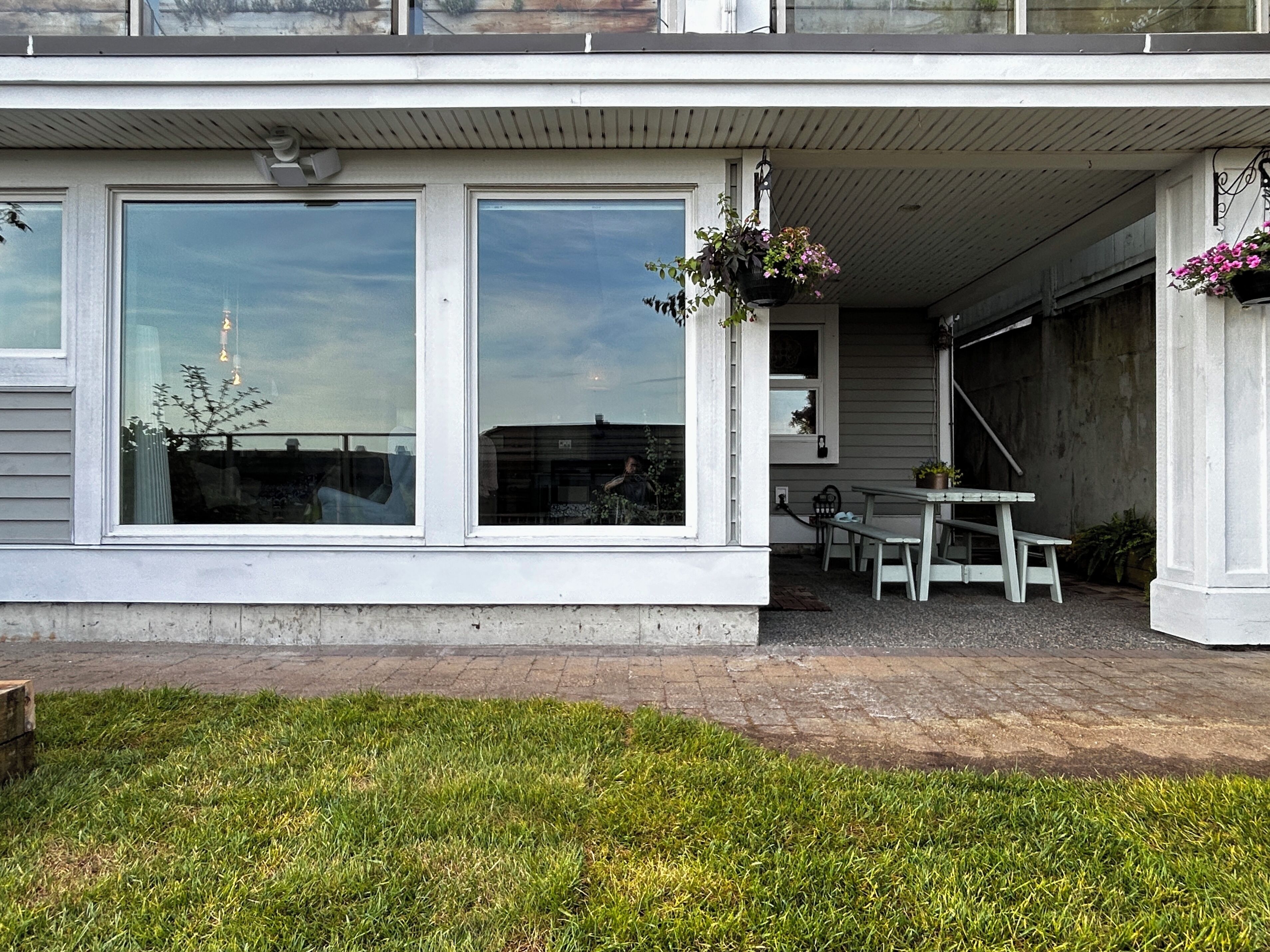 A house with large windows, a covered porch, and a small outdoor seating area.
