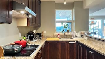 A kitchen with dark wood cabinets, granite countertops, a central island, and a window providing a view.