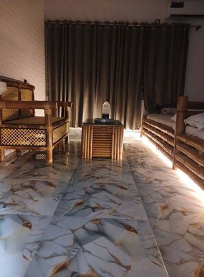 A room with a bed, a wooden chair, a small table, and a window with curtains. - Hotel Jaflong Point (Gowainghat)