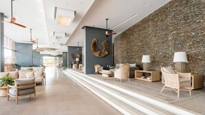 A spacious lobby with modern furniture, a stone wall, and ceiling fans. - Pleasant 1-bedroom apartment with AC in vibrant Rodadero (Rodadero)