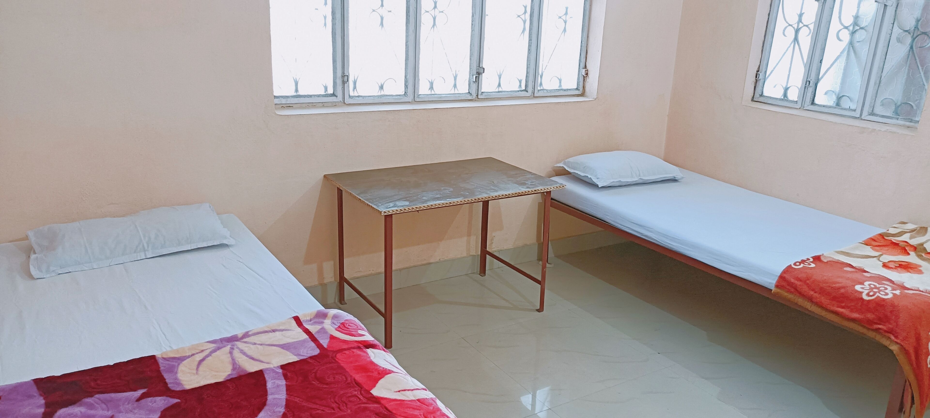 A room with two single beds, a small table, and a window.