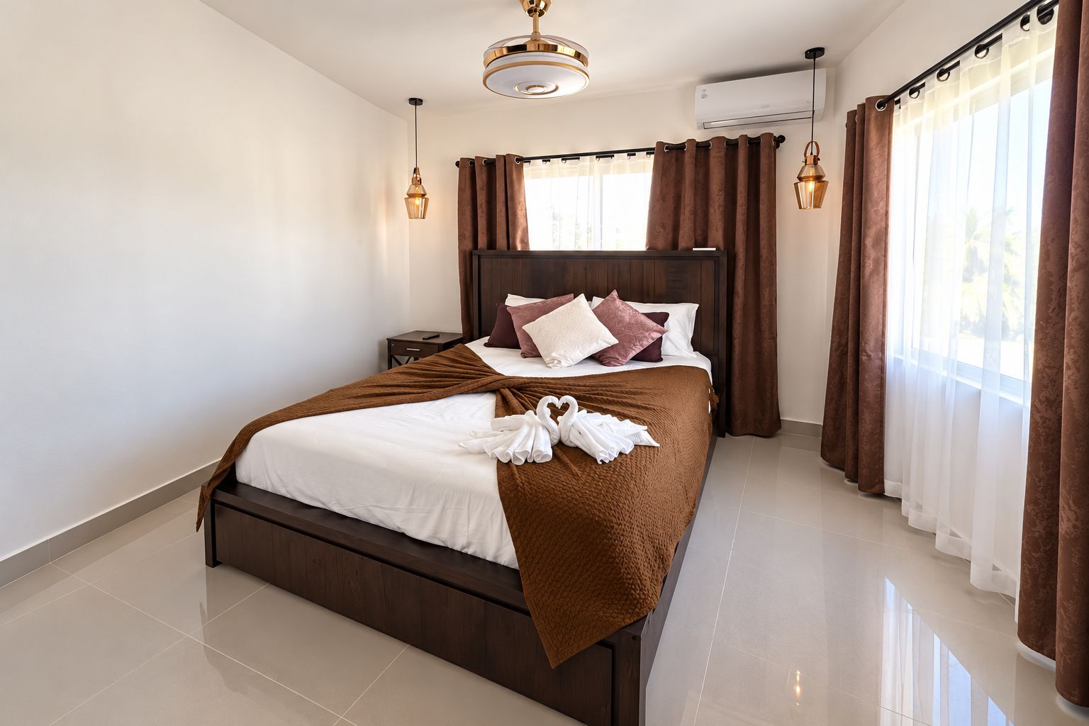 A hotel room with a large bed, a nightstand, a lamp, and a window with curtains.