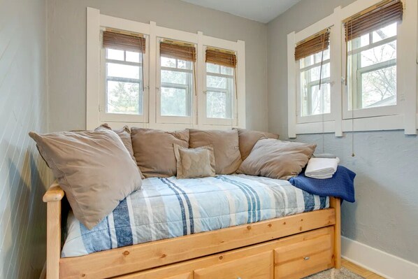 A bedroom with a bed, a window with blinds, and a door.