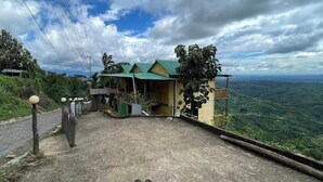 Un edificio con techo verde, una escalera que lleva a un balcón y vistas a un paisaje montañoso.