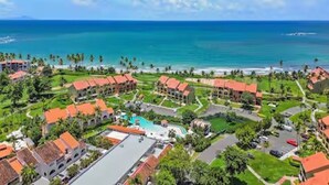 Un resort con varias edificaciones, piscina y vista al océano.