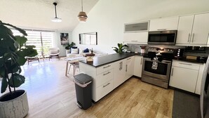 Una cocina moderna con armarios blancos, electrodomésticos de acero inoxidable y una isla central.