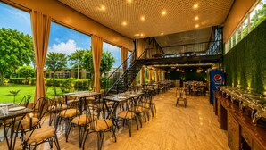 A restaurant with outdoor seating, a staircase, and a Pepsi refrigerator. - blue heaven resort jaipur  (Jamwa Ramgarh)
