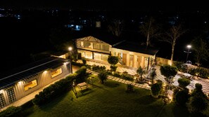 Una casa moderna con un amplio patio, piscina y un jardín bien iluminado.