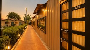 A corridor with a pathway, a building with a number sign, and a tree in the background. - blue heaven resort jaipur  (Jamwa Ramgarh)
