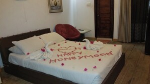 Een bed met een witte spreidek en handdoeken in de vorm van zwanen, met 'Happy Honeymoon' geschreven in bloemblaadjes.