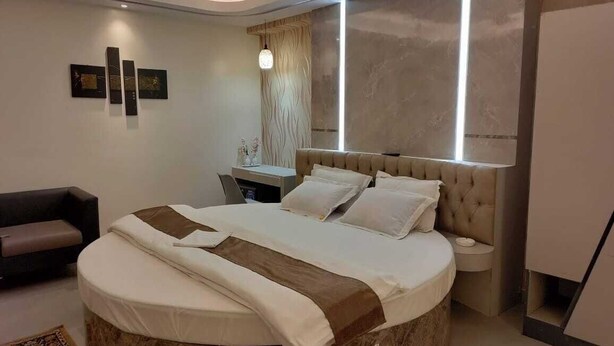 Een moderne slaapkamer met een rond bed, een nachtkastje en een bank.