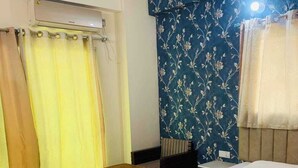 Een slaapkamer met een bed, een klein houten krukje, een bureau en een stoel.