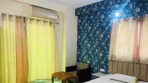 Een hotelkamer met een bed, een stoel, een tafeltje en gordijnen.