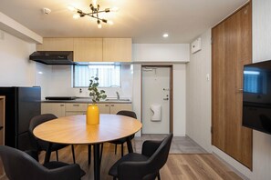 A modern kitchen with a dining area, a built-in oven, and a TV.