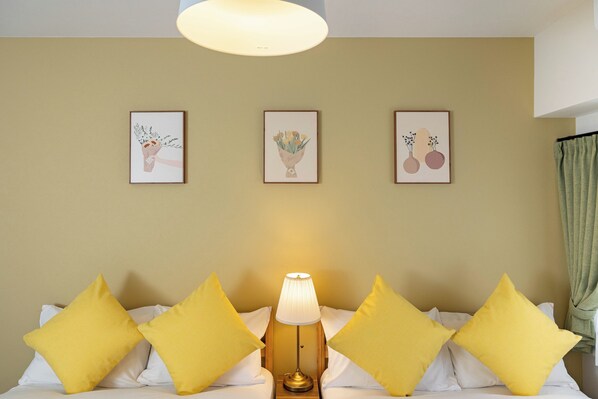 A hotel room with a bed, a lamp, and three framed pictures on the wall.