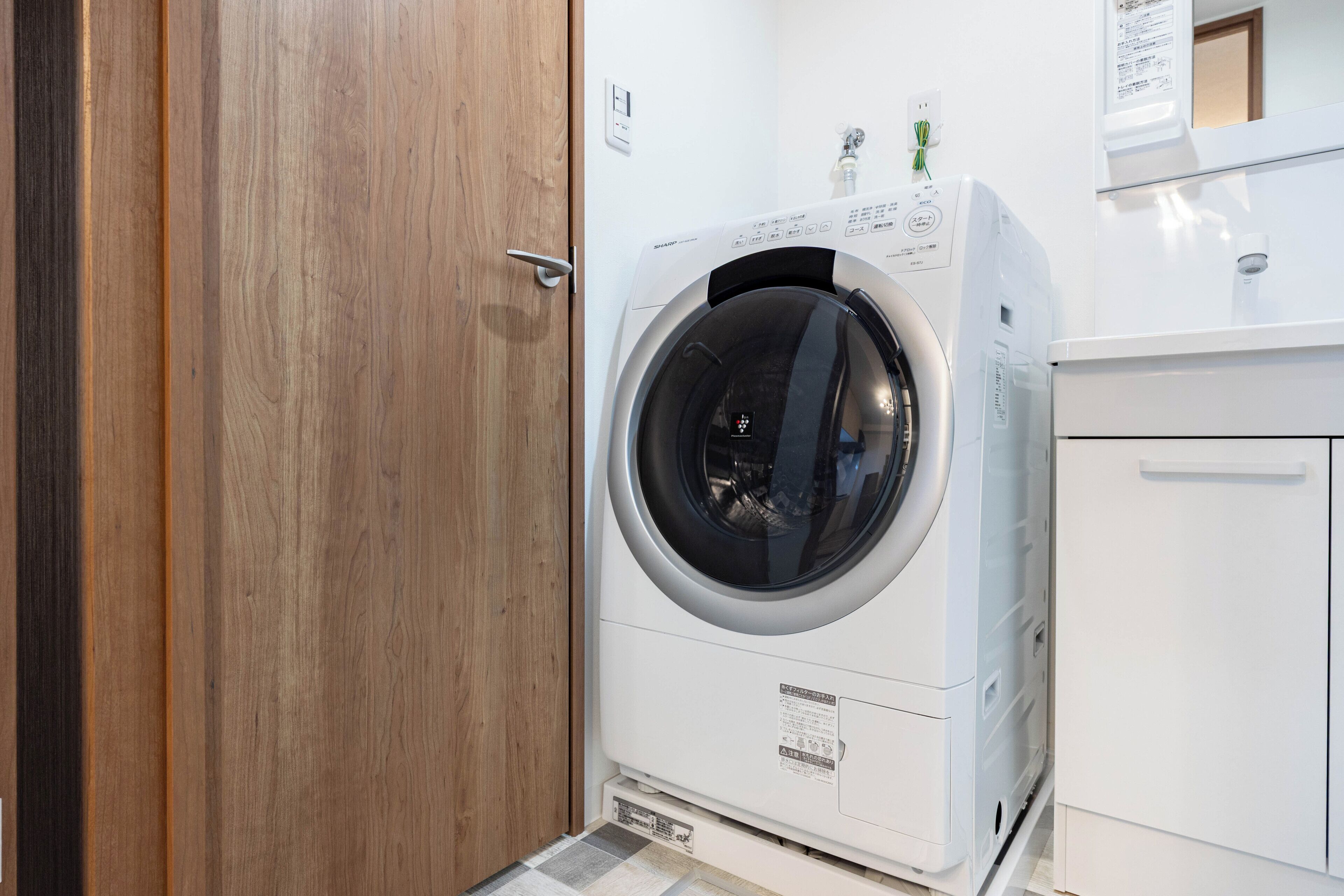 A front-loading washing machine in a laundry room with a wooden door and white cabinetry.
