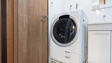 A front-loading washing machine in a laundry room with a wooden door and white cabinetry.