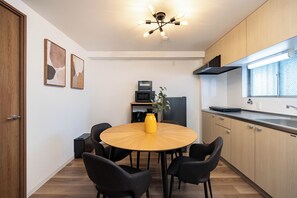 A modern kitchen with a round wooden table, black chairs, and a yellow vase.