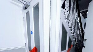 A hallway with white doors, a red arrow indicating direction, and a staircase with ornate railings. - Entire London center studio flat Victorian build/quiet/mins tube river/1 shower (London)