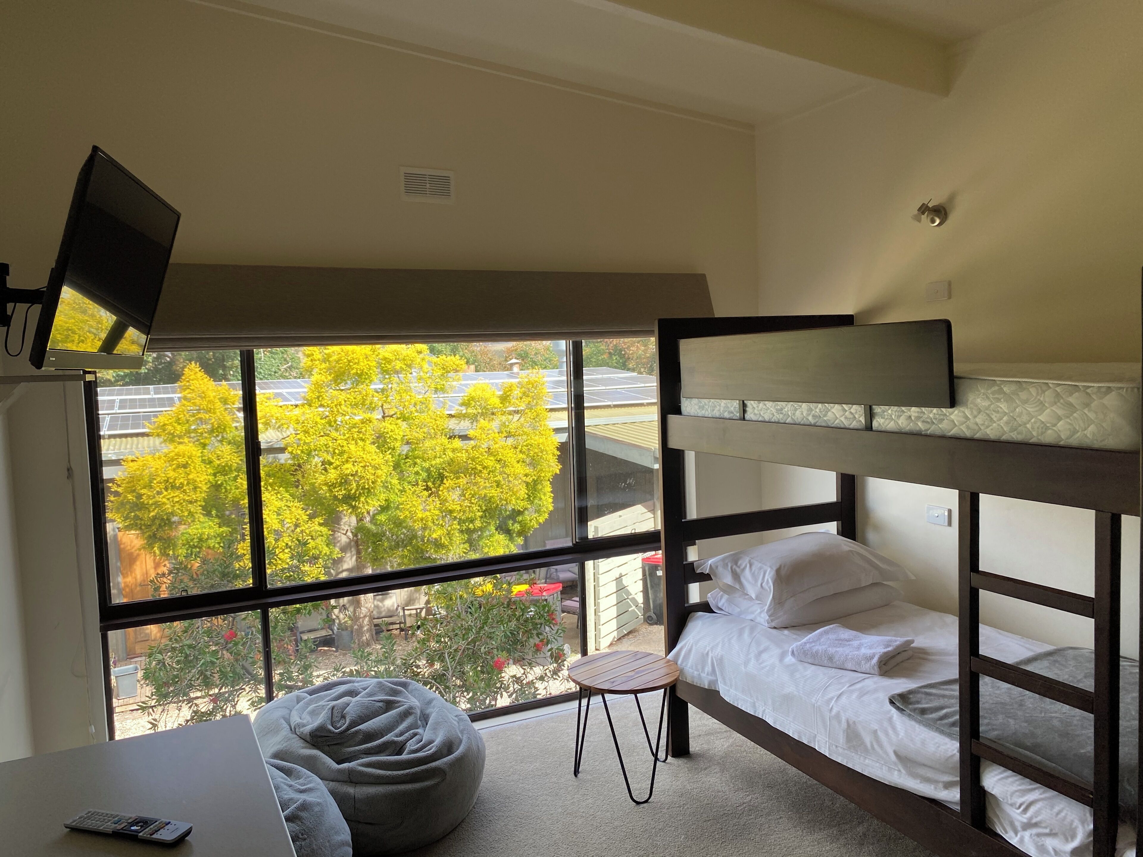 Habitación con literas, televisión, una mesita y vistas a árboles y edificios.