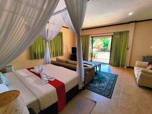 A hotel room with a bed, a sofa, a TV, and a view of the outdoors. - Ogtong Cave Resort (Santa Fe)