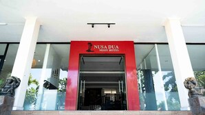 The entrance to Nusada Dua Moon Hotel with a red facade and glass doors. - Nusa Dua Moon Hotel (Nusa Dua)
