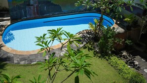 A swimming pool surrounded by a well-maintained garden with various plants and a tiled walkway. - Nusa Dua Moon Hotel (Nusa Dua)