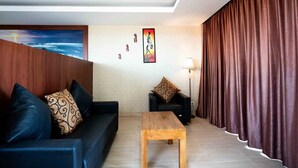 A living room with a sofa, a coffee table, a lamp, and a painting on the wall. - Nusa Dua Moon Hotel (Nusa Dua)