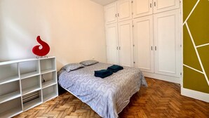 Un dormitorio con cama, armario blanco y una escultura abstracta roja.