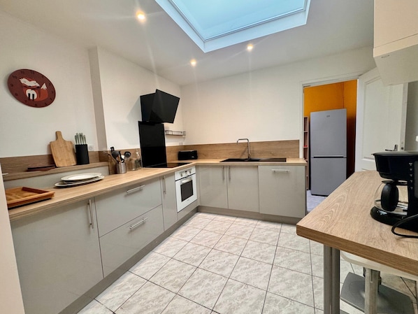 A modern kitchen with a skylight, a built-in oven, and a refrigerator.