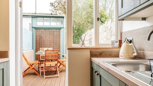 Uma cozinha com mesa e cadeiras de madeira, uma janela com vista para árvores e um rádio.