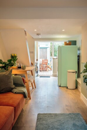 A modern kitchen with a green refrigerator, wooden dining table, and a cozy seating area with a sofa and chairs.