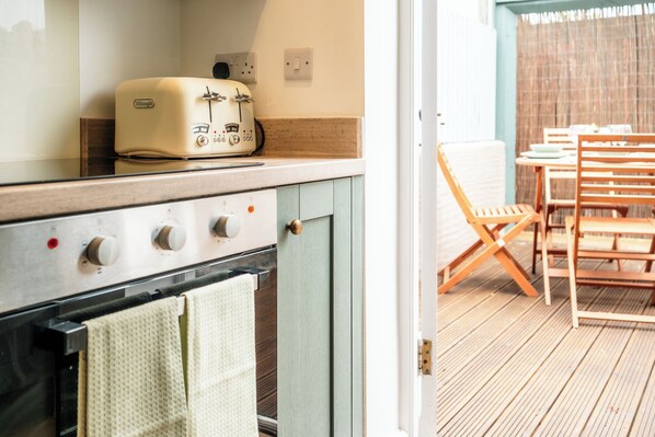 Una cocina con un tostador antiguo, un horno y una zona de comedor con sillas de madera.