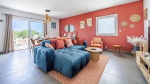 A living room with a blue sofa, a round coffee table, and a red accent wall. - Nice house in the hills, with private jacuzzi, sunny terrace! (Nice)