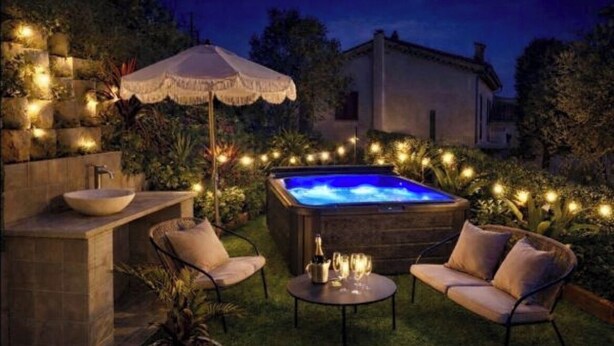 A hot tub surrounded by outdoor furniture, a stone sink, and string lights. - Nice house in the hills, with private jacuzzi, sunny terrace! (Nice)