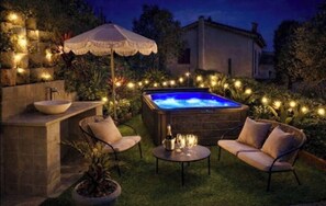 A hot tub surrounded by outdoor furniture, a stone sink, and string lights. - Nice house in the hills, with private jacuzzi, sunny terrace! (Nice)