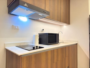 A modern kitchen with a built-in microwave, a gas stove, and wooden cabinets.