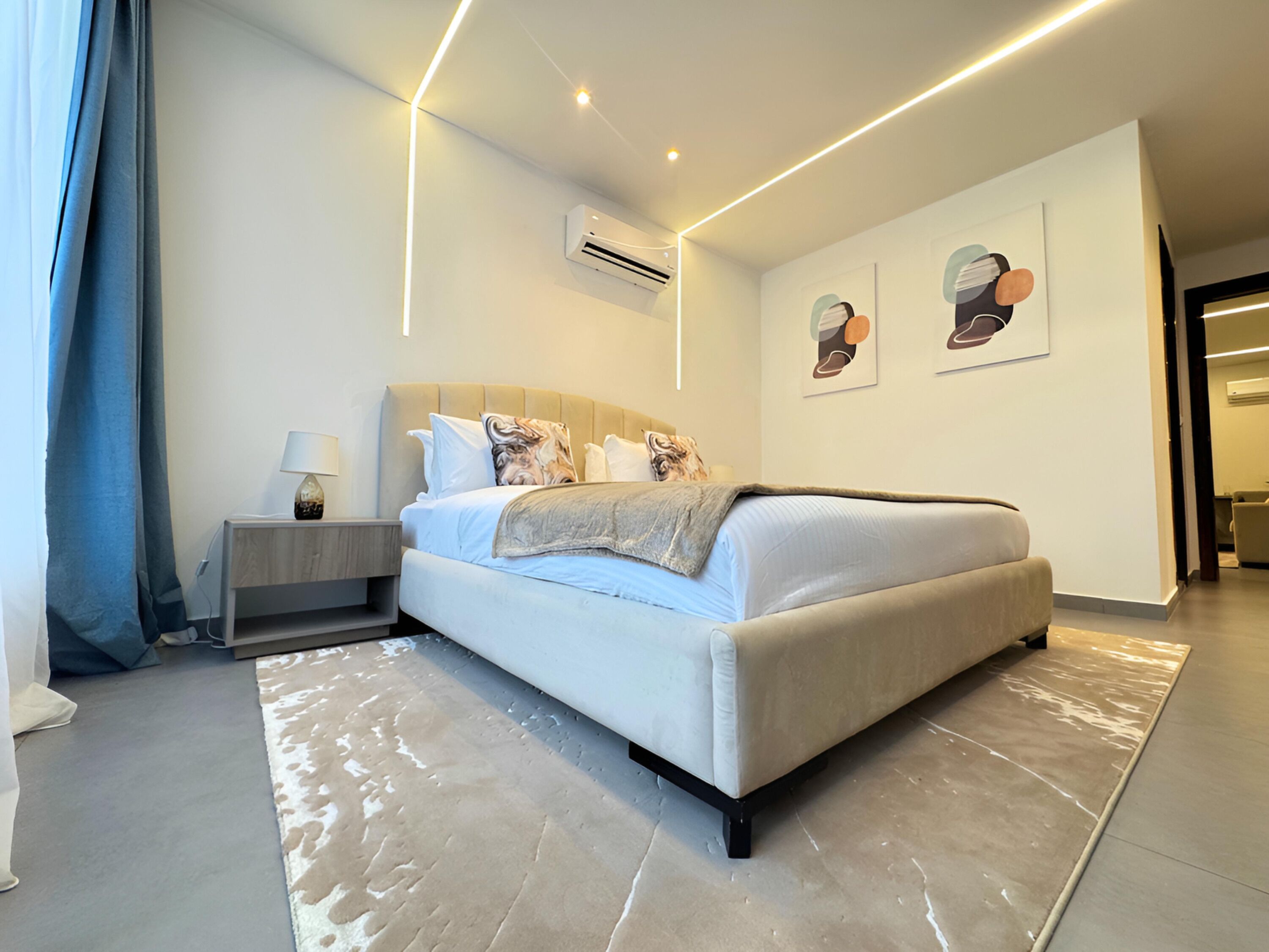 Ein modernes Schlafzimmer mit einem Bett, einem Nachttisch und Kunstwerken an der Wand.
