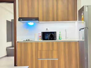 A modern kitchen with wooden cabinets, a microwave, a sink, and a stainless steel refrigerator.