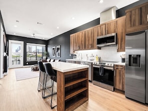 Una cocina moderna con gabinetes de madera, electrodomésticos de acero inoxidable y una isla grande con taburetes de bar.