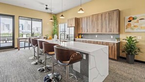 A modern kitchen with a large island, bar stools, and wooden cabinets.