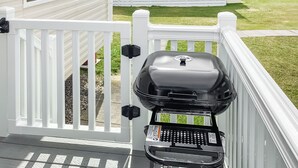 En grill på en terrasse med hvide gelændere.