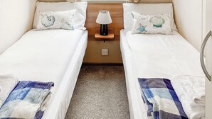 Et værelse med to senge, et vindue med gardiner, et natbord med lampe, og udsigt udad.