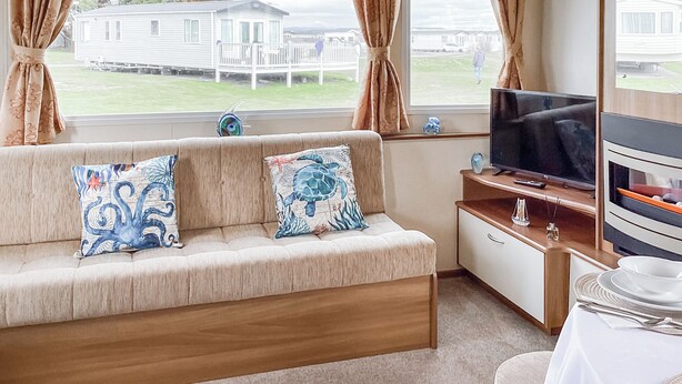 Et værelse med sofa, TV og udsigt til huse.
