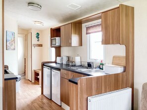 A compact kitchen with wooden cabinets, a microwave, a toaster, and a sink.