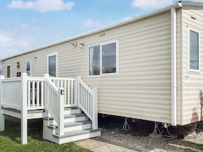 A mobile home with a white exterior, a front porch with a staircase, and a visible number '39' on the side.