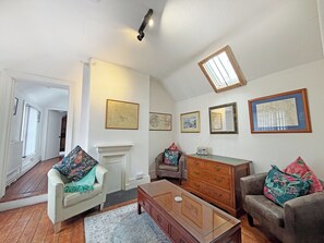 A living room with a fireplace, a sofa, a coffee table, and a TV.