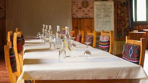 A long dining table with chairs, clear glass bottles, and a white tablecloth. - Samyae Resort (Jakar)