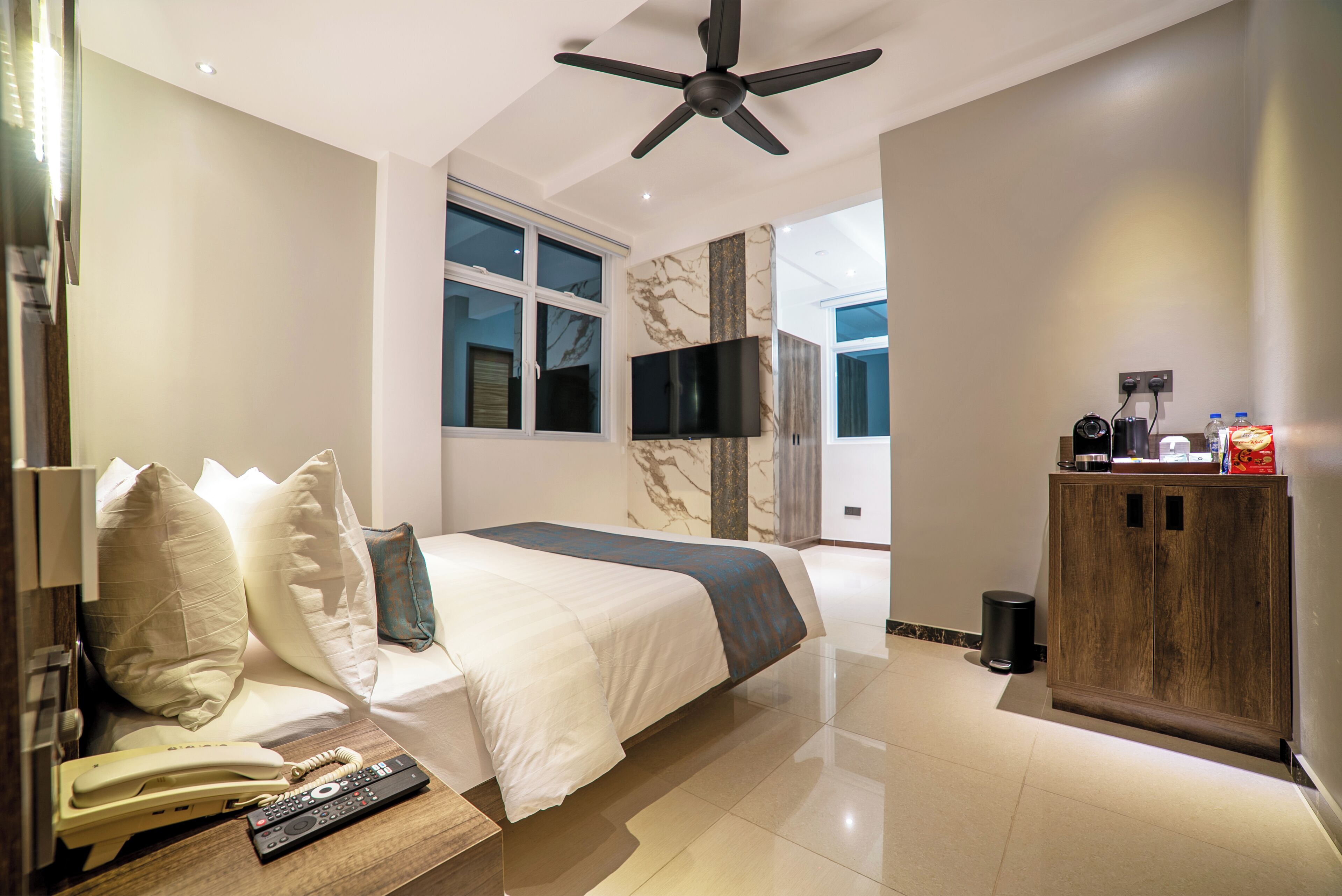 Una habitación de hotel con una cama, televisión, un armario de madera y un teléfono.