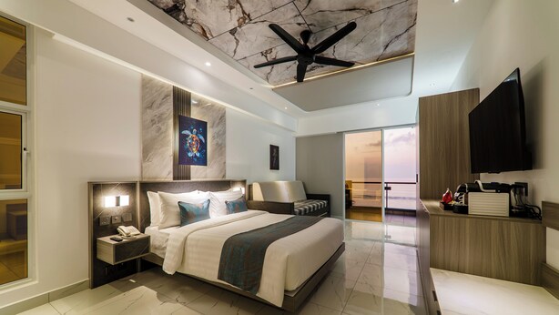 A modern hotel room with a large bed, a ceiling fan, a flat-screen TV, and a marble floor. - Samann Blue (Hulhumale)